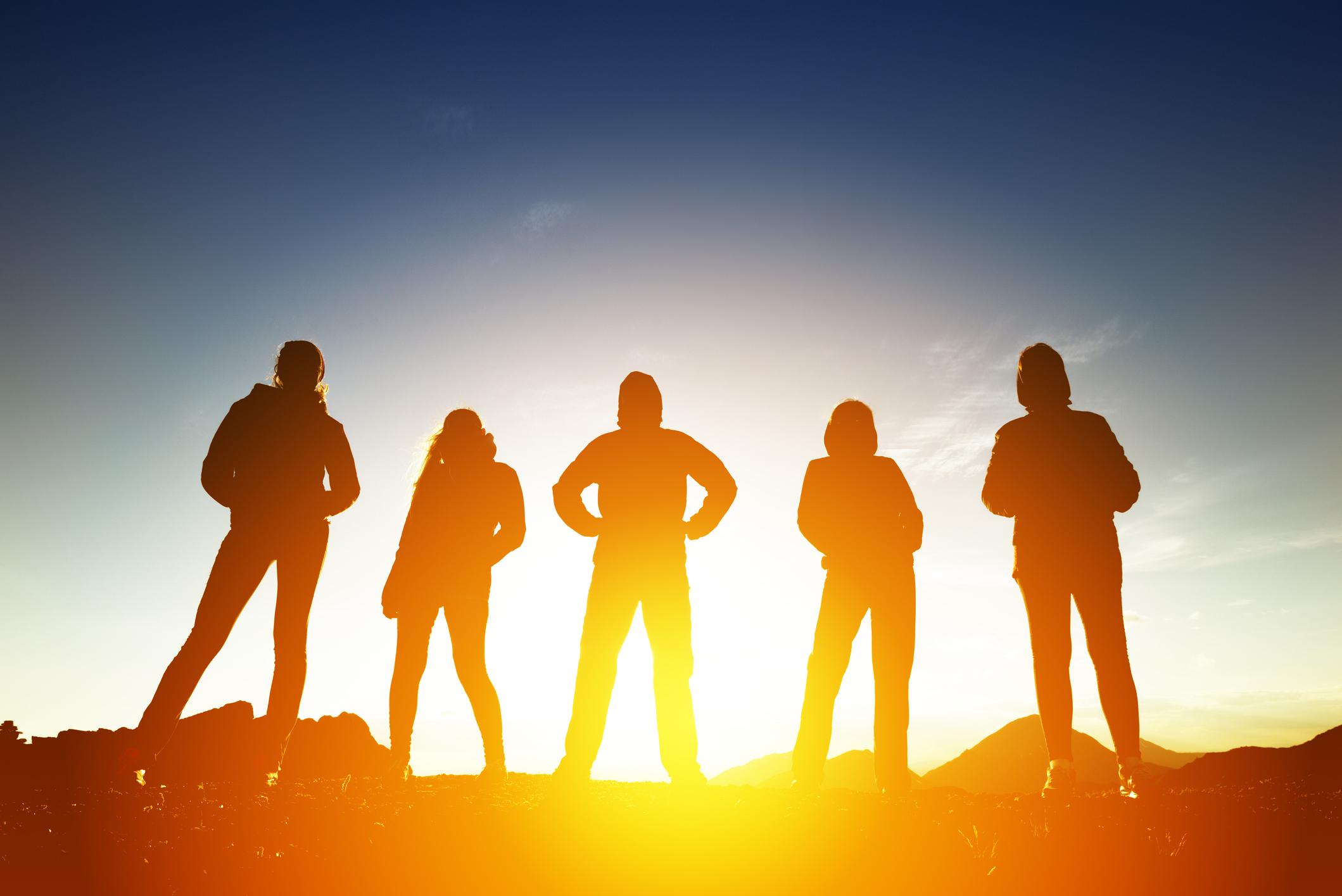 Group Of Five Peoples In Silhouettes At Sunset